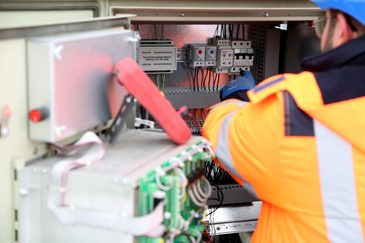 Engineer inspecting an industrial electrical control panel